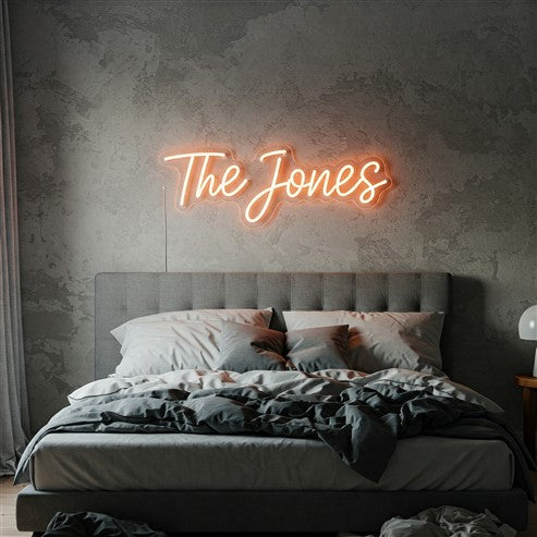 Modern bedroom featuring a warm orange neon sign reading 'The Jones,' adding a personalised and cosy touch to the space with soft ambient lighting.